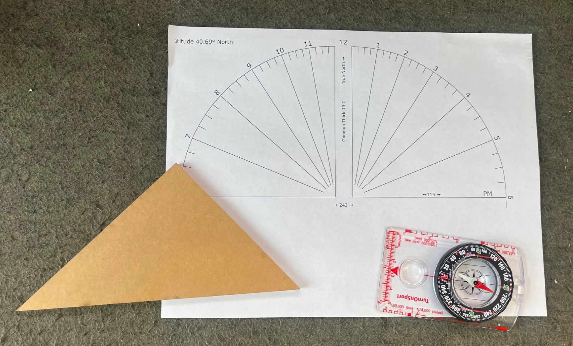 Printed sundial template with hour lines, a triangular gnomon, and a compass.